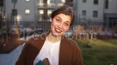 一位微笑的年轻房地产经纪人在一座新城市建筑的院子里的肖像。 幸福的女人，房地产